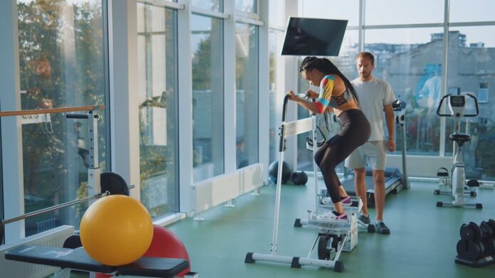 Personal trainer guides a client on exercise equipment while creating product demo videos