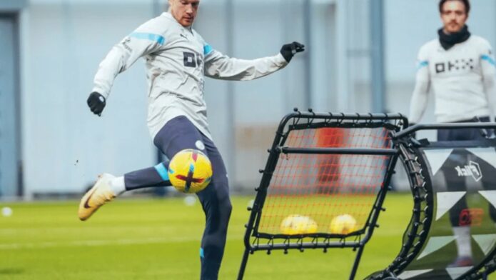 A soccer player shooting practice ball into the net