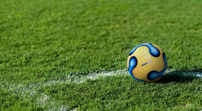 Blue-yellow ball placed in a corner of a grass soccer pitch